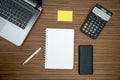 An office table working enviroment. Notepad, sticky note, pen plant, calculator and a lap top on a brown striped zebrawood design Royalty Free Stock Photo