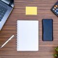 An office table working enviroment. Notepad, sticky note, pen plant, calculator and a lap top on a brown striped zebrawood design Royalty Free Stock Photo