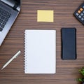 An office table working enviroment. Notepad, sticky note, pen plant, calculator and a lap top on a brown striped zebrawood design Royalty Free Stock Photo