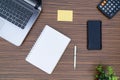 An office table working enviroment. Notepad, sticky note, pen plant, calculator and a lap top on a brown striped zebrawood design Royalty Free Stock Photo