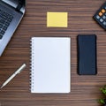 An office table working environment. Notepad, sticky note, pen plant, calculator and a lap top on a brown striped zebrawood design Royalty Free Stock Photo