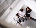 Office, tablet and business people in stairs together for chat, gossip or discussion with high angle. Work, friends and Royalty Free Stock Photo