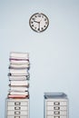 Office wall with clock stack of paperwork in inbox on file cabinet