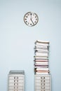 Office wall with clock stack of paperwork in outbox on file cabinet