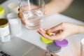 Office women pouring the pills vitamin,supplements out of the bottle on hand and holding a glass of water at home office. Royalty Free Stock Photo