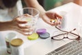 Office women pouring the pills vitamin,supplements out of the bottle on hand and holding a glass of water at home office. Royalty Free Stock Photo