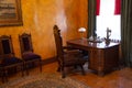 An office with wooden chairs, a table and a brown armchair in vintage style. Antique furniture by the window. Historical value