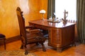 An office with a wooden table and a brown armchair in vintage style. Antique furniture by the window. Historical value