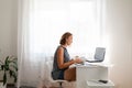 Office work, freelance and business. Young blonde woman reading a book and working with a computer. In the background is Royalty Free Stock Photo