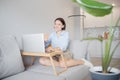 Office work home concept. Happy young woman teacher in headphones greets in video chat with laptop students