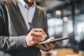 An office worker actively takes notes during a meeting, utilizing a smart pen on a tablet to digitize handwritten content in a Royalty Free Stock Photo