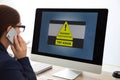 Office worker in front of computer with warning about virus attack on screen Royalty Free Stock Photo