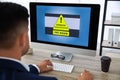 Office worker in front of computer with warning about virus attack on screen Royalty Free Stock Photo