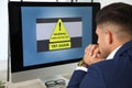 Office worker in front of computer with warning about virus attack on screen Royalty Free Stock Photo