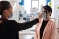 Office worker getting body temeperature checked with digital thermometer Royalty Free Stock Photo