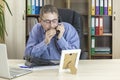 Office worker gossiping on the phone with his hand on the receiver. The manager looks at the boss`s photo. Spreading rumors