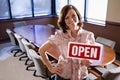 Office worker holding open sign in empty boardroom