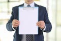 Office worker holds clipboard with blank paper in hallway