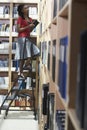 Office Worker On Ladder In File Storage Room