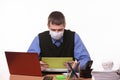 Office worker in a medical mask at the workplace looks at the tablet screen