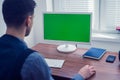 Office worker sitting at computer with Chromakey on monitor