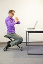 Office worker sitting on kneeling stool, exercising during short break in work