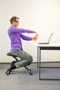 Office worker sitting on kneeling stool, exercising during short break in work Royalty Free Stock Photo