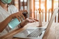 Office worker working from home during coronavirus outbreak cleaning her hands with sanitizer gel and wearing protective mask. Royalty Free Stock Photo