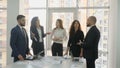 Office workers, employees of a large company, two young men and three young women standing near a table with documents