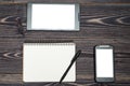 Office workplace with blank notebook notepad, pen, tablet and smartphone with white screen on wooden table, copy space. Mock up Royalty Free Stock Photo