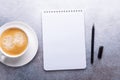 Office workplace with cup of coffee, note pad and pen. Stone background. Top view Royalty Free Stock Photo