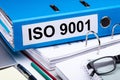 Folder With Iso 9001 Text And Office Supplies Over Desk