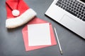 Office workplace with laptop, Santa`s cap, accessories on gray background. Top view, copy space. Royalty Free Stock Photo
