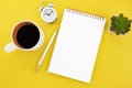 Office workplace minimal concept. Blank notebook with coffee, cactus, alarm clock and pencil on yellow background. Royalty Free Stock Photo