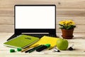 Office workplace with open laptop and white screen. Green and yellow notebooks, markers, pencils lie on the table. Royalty Free Stock Photo