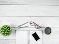 Office workspace top view copy space ,Smartphone black screen on black page notebook with glasses and two silver pen on white wood Royalty Free Stock Photo