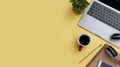 office workspace yellow desk table with laptop, coffee, mobile, notebook, plant