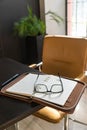 Office workstation. Yellow chair and black desk in home office. The desk holds an open organizer, pen and glasses