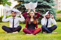 Office yoga. Three young employees in a lotus pose are sitting on green grass and meditate. Recreation of office staff. Healthy li Royalty Free Stock Photo