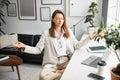 Office zen. Calm european businesswoman meditating with closed eyes in lotus position, feeling peaceful and balanced Royalty Free Stock Photo