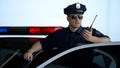 Officer standing near police car and informing about crime on two-way radio