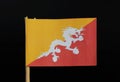 A official Flag of Bhutan on toothpick on black background. Consists of yellow and red side with white dragon Royalty Free Stock Photo