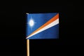 A official flag of marshall islands on wooden stick on black background. Marshall islands are located in pacific ocean and belongs