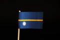 A official flag of nauru on wooden stick on black background. A nauru is island state and belongs to oceania