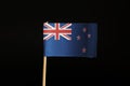 A official Flag of New Zealand on wooden stick on black background created by paper. New Zealand belongs to Australia continent.
