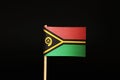 A official Flag of Vanuatu on wooden stick on black background. It is island state and belongs to Oceania