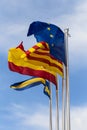 Official flags of the city of Salou, Spain, Catalonia and The European Union EU waving against a blue sky. Vertical. Royalty Free Stock Photo
