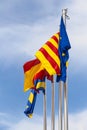 Official flags of the city of Salou, Spain, Catalonia and The European Union EU waving against a blue sky. Vertical. Royalty Free Stock Photo