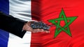 Official hand holding toy tank against France and Morocco flag, armed forces