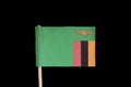 A official, national flag of Zambia on toothpick on black background. Zambia has flag contain eagle and tricolour on green field.